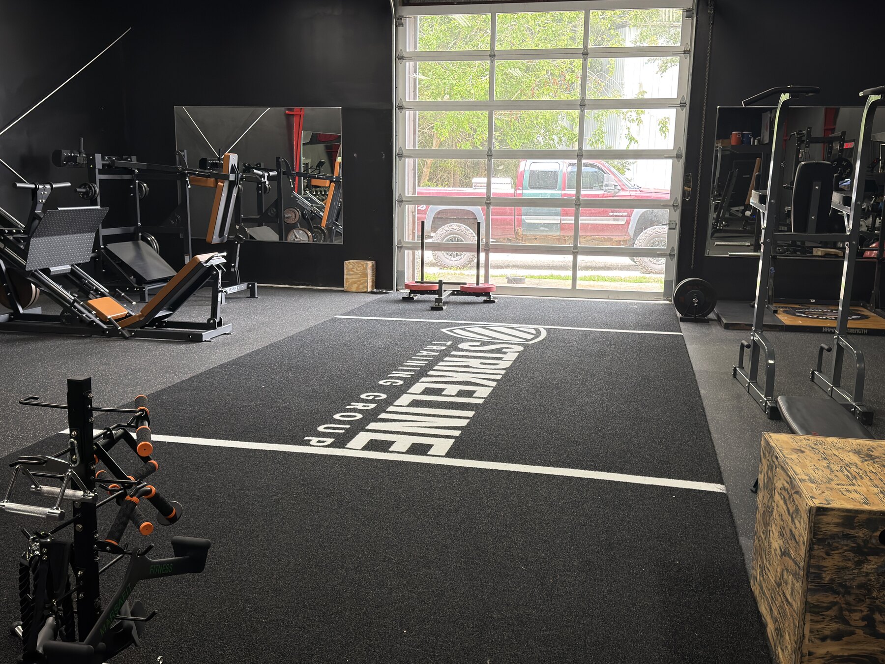 Strikeline-branded indoor turf with a sled and surrounding strength equipment